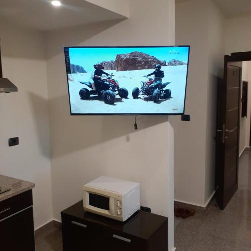 a tv hanging on a wall with two people riding motorcycles at Tamrah Suites Hotel in Amman