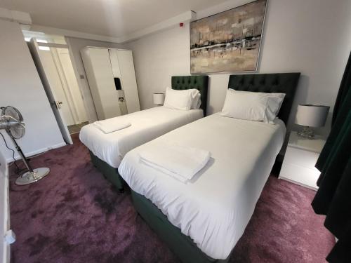 ロンドンにあるLondon Central Modern Apartment Charltonの紫色のカーペットフロアの客室で、ベッド2台が備わります。