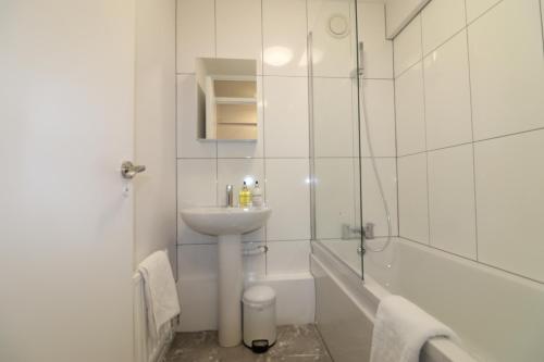 a white bathroom with a sink and a bath tub at London Central Modern Apartment Charlton in London