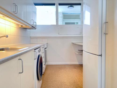 Biała kuchnia ze zlewem i zmywarką do naczyń w obiekcie One Bedroom Apartment In Valby, Langagervej 64, 2 w Kopenhadze