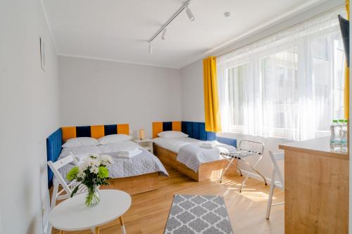 a bedroom with two beds and a table with flowers on it at Porta Baltica - pokoje Sopot in Sopot