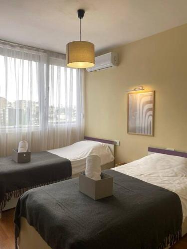a bedroom with two beds and a large window at Etern Stays IEG - Pristine Apartment in Prishtinë