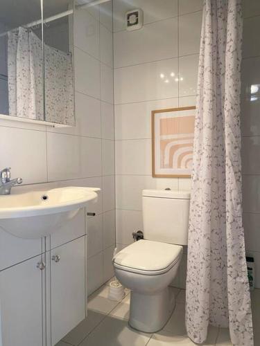 a white bathroom with a toilet and a sink at Etern Stays IEG - Pristine Apartment in Prishtinë
