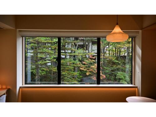 een raam in een kamer met uitzicht op een bos bij URAKUSATSU TOU - Vacation STAY 75063v in Kusatsu