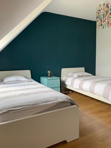 - 2 lits dans une chambre avec un mur vert dans l'établissement Villa des Roseaux, à Bénodet