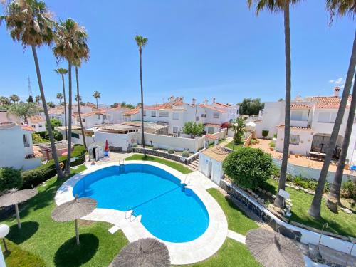 uma vista superior de uma piscina com guarda-sóis em Townhouse w/sea view & garden em Estepona
