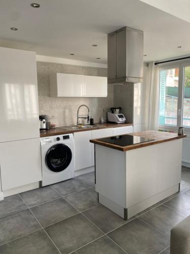 La cuisine est équipée de placards blancs et d'un lave-vaisselle. dans l'établissement Superbe appart à Clermont-Ferrand Parking privé, à Clermont-Ferrand