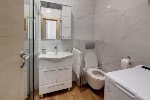 a white bathroom with a toilet and a sink at PORTOFINO, With Free Private GARAGE in Novi Sad