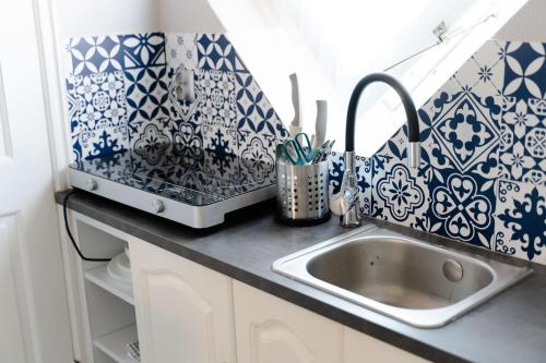 a kitchen counter with a sink and blue and white tiles at Porta Baltica - pokoje Sopot in Sopot