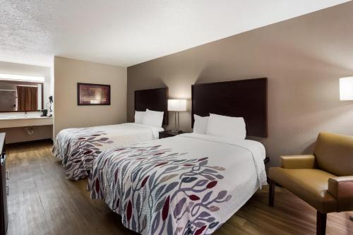 ein Hotelzimmer mit 2 Betten und einem Stuhl in der Unterkunft Red Roof Inn Columbia, SC Airport in Columbia