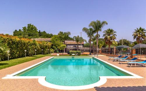 uma piscina num quintal com cadeiras e árvores em Villa Aura em Piedimonte Etneo