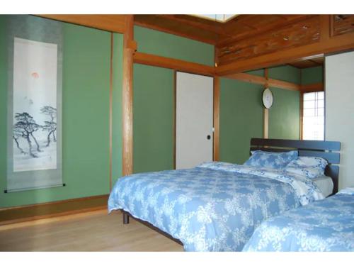 a bedroom with two beds and a clock on the wall at Minpaku Yagi - Vacation STAY 14700 in Ise