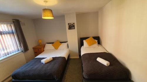 two beds in a small room with a window at Contractors, City Centre, Parking, 3 Double Rooms, Netflix, Cosy! in Coventry