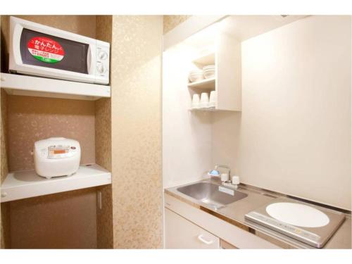 2 fotos de una cocina con fregadero y microondas en Hotel Hanabi - Vacation STAY 67139v, en Tokio