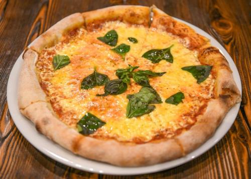 a pizza sitting on a plate on a table at Hotel Keto in Podgorica
