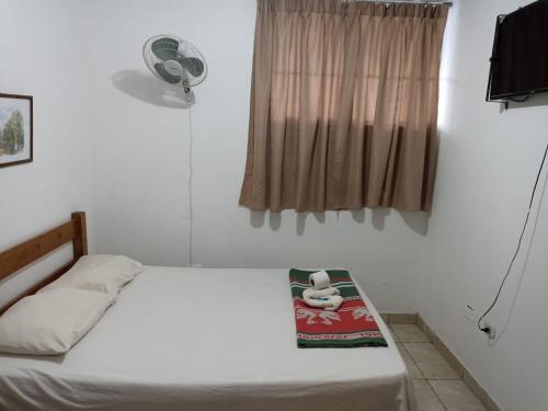 a bedroom with a bed and a window with a fan at HOSTAL PARIS in Piura