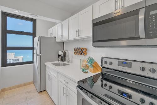 a kitchen with white cabinets and a stainless steel appliances at Beach Oasis with Ocean & City Views with FREE Parking! in Honolulu