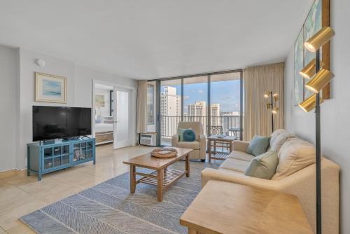 a living room with a couch and a tv at Beach Oasis with Ocean & City Views with FREE Parking! in Honolulu
