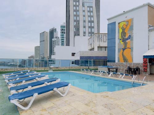 einen Pool mit Liegestühlen und ein Wandbild an einem Gebäude in der Unterkunft Hotel Costa del Sol in Cartagena de Indias