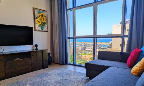 a living room with a couch and a large window at By the Sea in Ashkelon