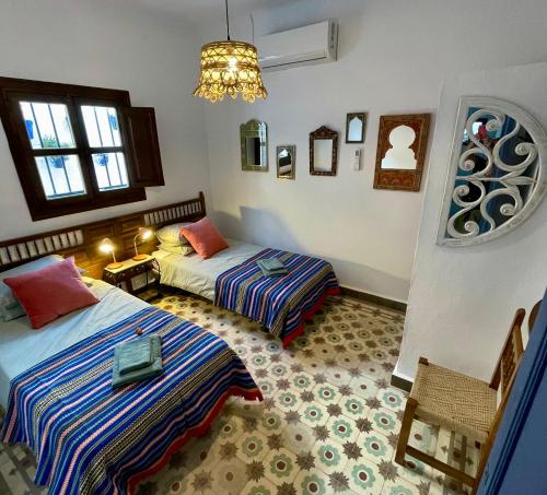 a bedroom with two beds and a chandelier at Casa Amigos Sorvilan- La Palmera in Sorvilán