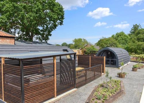 a garden with a fence and a greenhouse at Hill Farm Retreat in Wangford