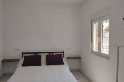 um quarto branco com uma cama e uma janela em CASA INDEPENDIENTE SUANCES - 800m2 de jardín - Parking - Wifi5G em Cortiguera