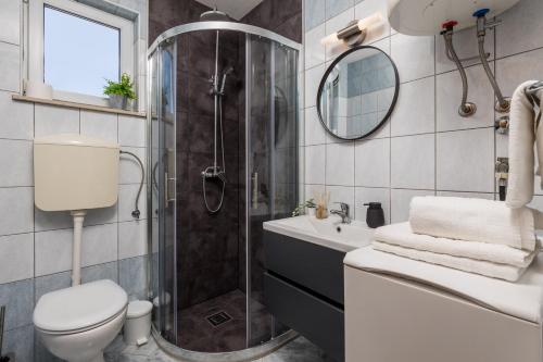 een badkamer met een douche, een toilet en een wastafel bij Apartments More in Klenovica
