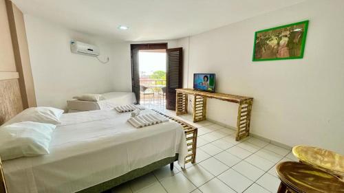 um quarto com uma cama, uma mesa e uma janela em Hotel Antibes em Natal