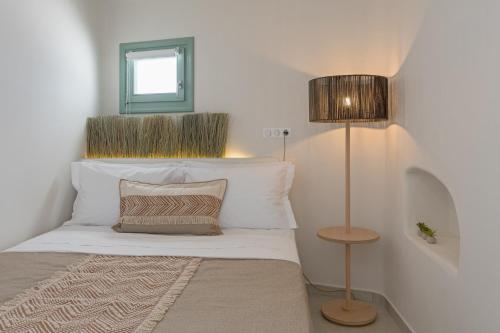 a bedroom with a bed with white sheets and a lamp at Anestorema House in Astypalaia