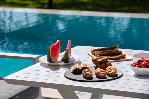 a table with plates of food on a table near a pool at Averto Villas with private pool in Nydri