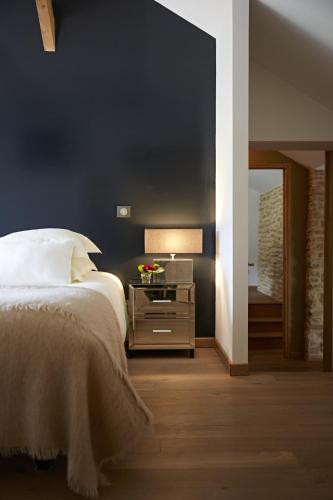 une chambre avec un lit et une table avec une lampe dans l'établissement Hameau de Blagny, à Puligny-Montrachet