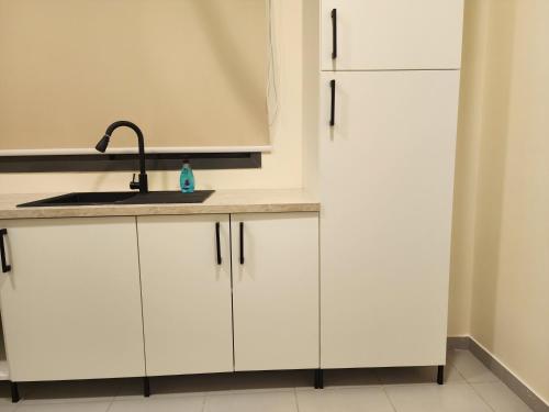 a kitchen with white cabinets and a sink and a refrigerator at Nesaj Villa in Dammam