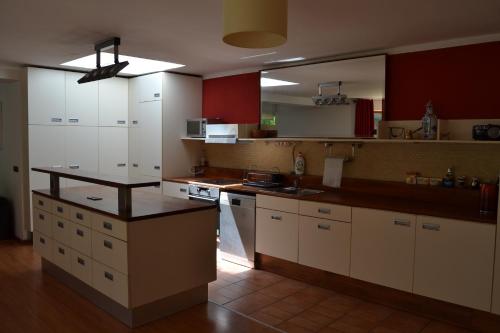 a large kitchen with white cabinets and red at Large house with parking, 30 min to Prague center in Úvaly