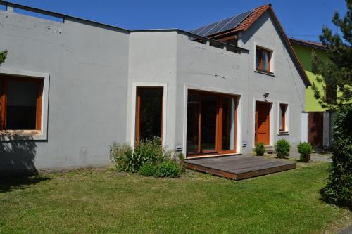 une maison blanche avec une terrasse en bois dans la cour dans l'établissement Large house with parking, 30 min to Prague center, à Úvaly