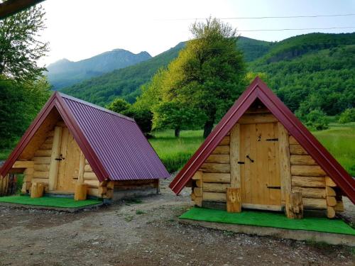 two wooden buildings with red roofs in a field at Bungalows Malagić in Gusinje