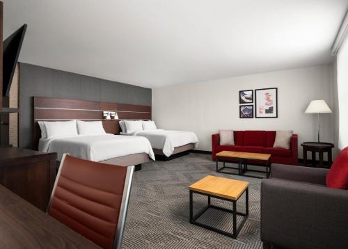 Habitación de hotel con 2 camas y sofá rojo en Holiday Inn - Cincinnati - Liberty Way, an IHG Hotel en West Chester