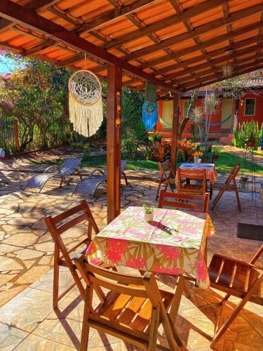 a patio with a table and chairs under a wooden pergola at Pousada Jardim de Minas in Serra do Cipo