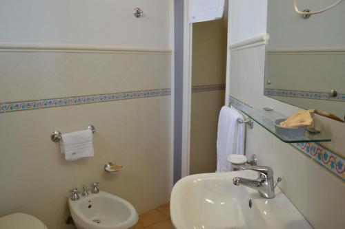 a bathroom with a sink and a toilet and a mirror at HOTEL Cala Buguto in Custonaci