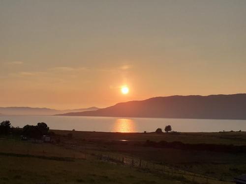 a sunset over the water with mountains in the background at Ramadale Stornoway in Stornoway
