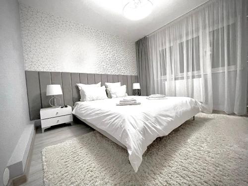 a bedroom with a large white bed and a window at Golden Valley Apartment in Sibiu