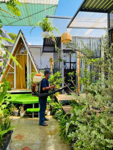 a man standing in a garden with a hose at Trầm Homestay in Thôn An Hòa