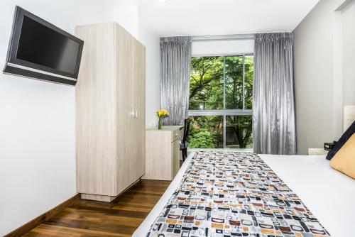 a hotel room with a bed and a flat screen tv at Hotel Asturias Medellin in Medellín