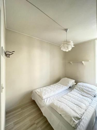 a white bedroom with a bed and a chandelier at 1St Floor Oasis - Parking/WiFi in Stavanger