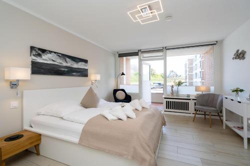 a white bedroom with a large bed with white pillows at Strandwärts in List