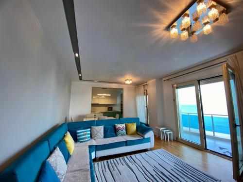 Sala de estar con sofá azul y vistas al océano en Reina Suite en Durrës