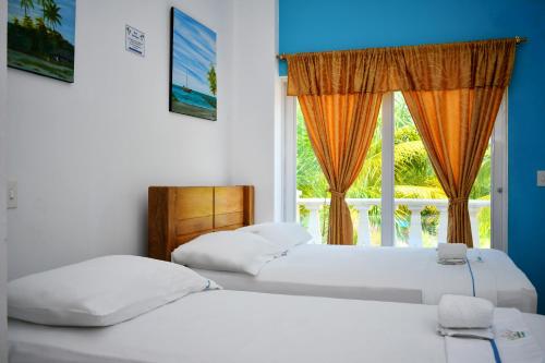 two beds in a room with a window at Hotel Isla Mágica in Coveñas