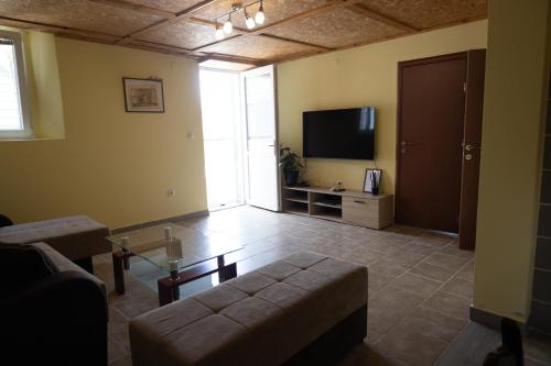 uma sala de estar com um sofá e uma televisão de ecrã plano em Apartman Delać em Tivat