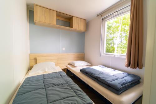 a bedroom with two beds and a window at Mobil-home 6/8 personnes - Camping Siblu **** Domaine de Dugny in Onzain