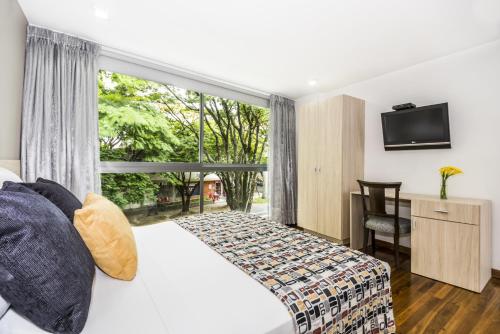 a hotel room with a bed and a large window at Hotel Asturias Medellin in Medellín